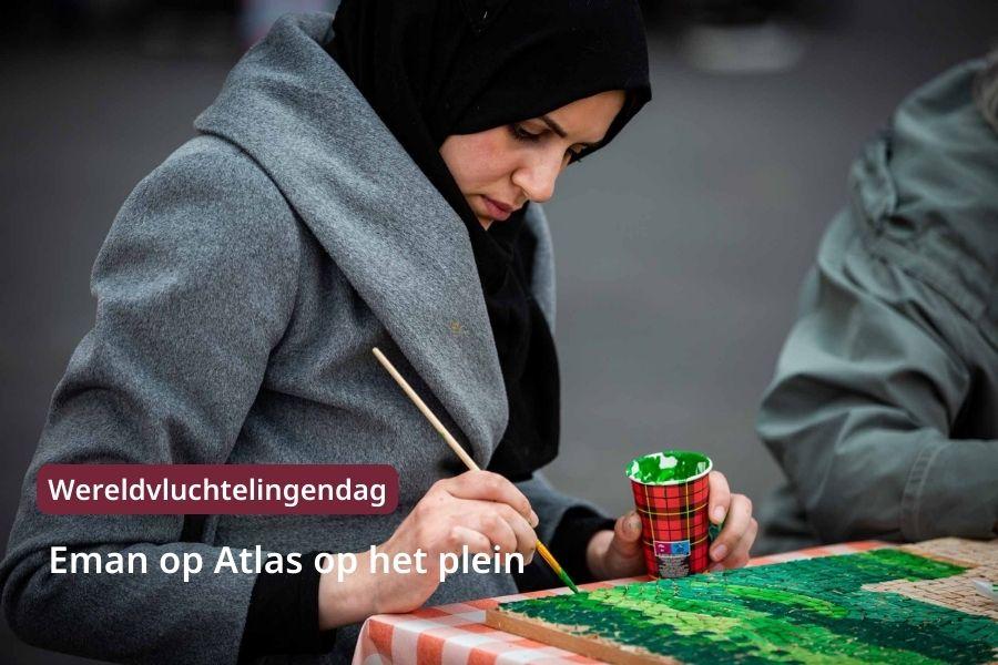 Kunstenares Eman schildert de mozaïek. Ze draagt een zwarte hoofddoek en heeft een grijze jas aan. De mozaïek schildert ze in met groene verf.